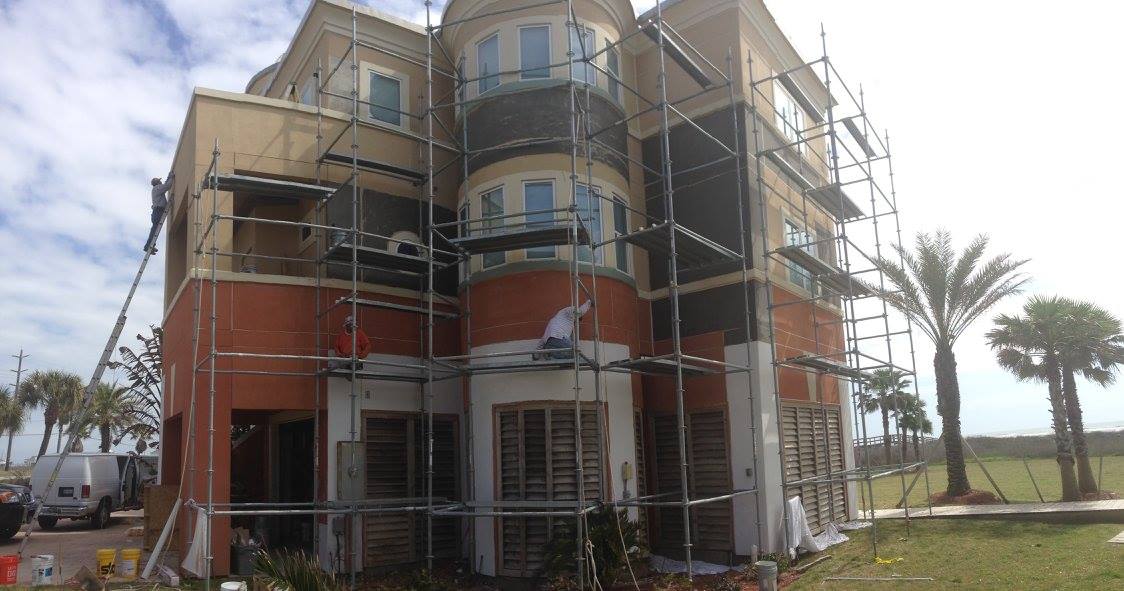 A large building with scaffolding around it is being painted.