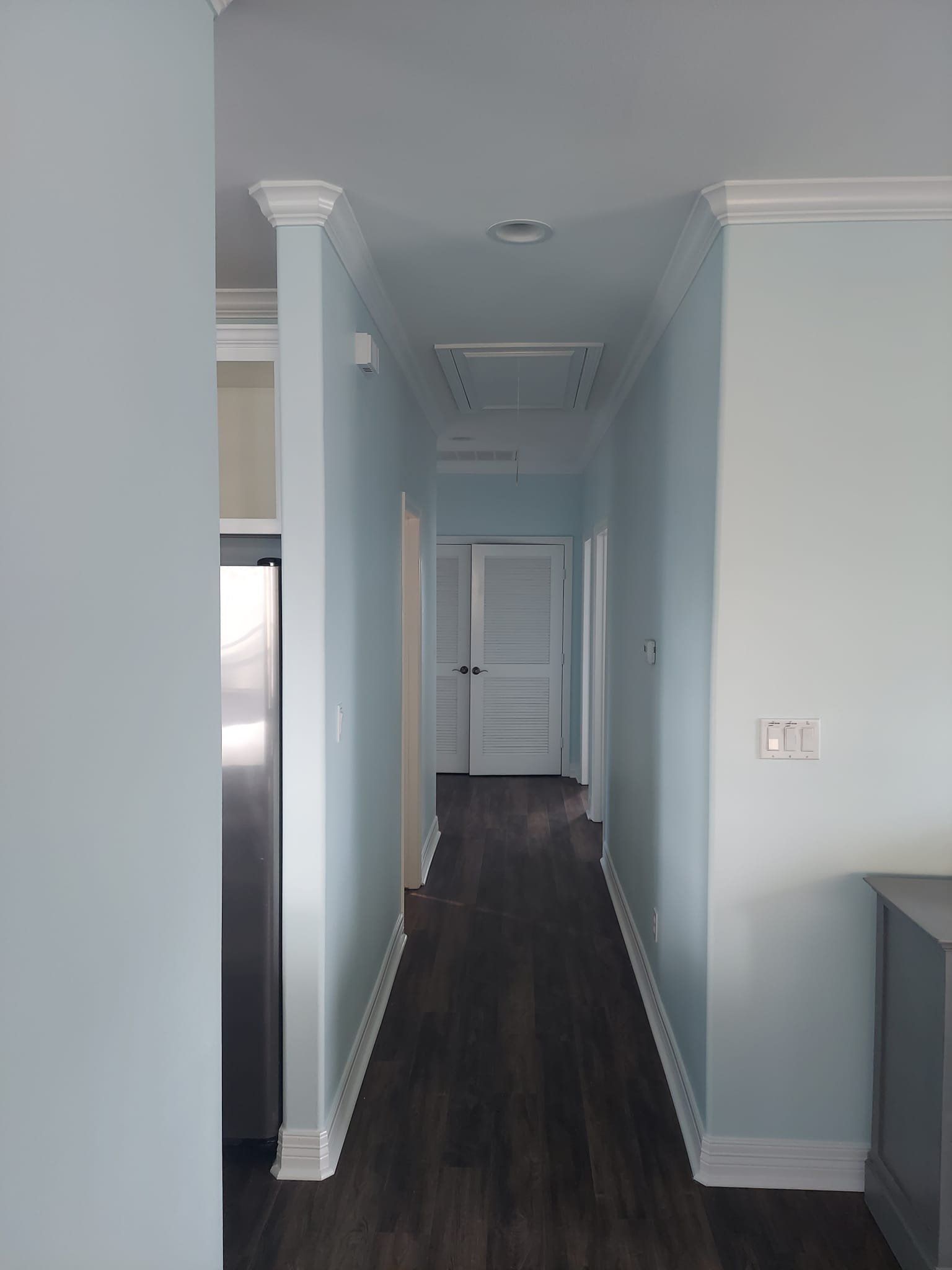 A long hallway in a house with blue walls and white trim.