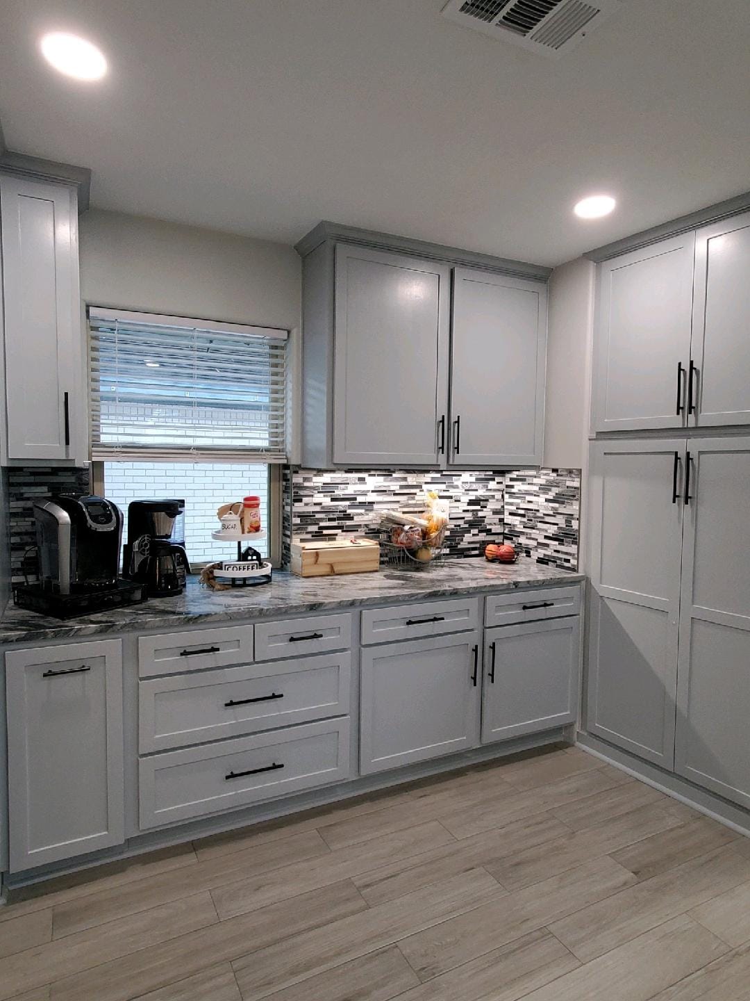 A kitchen with white cabinets , granite counter tops , and a window.