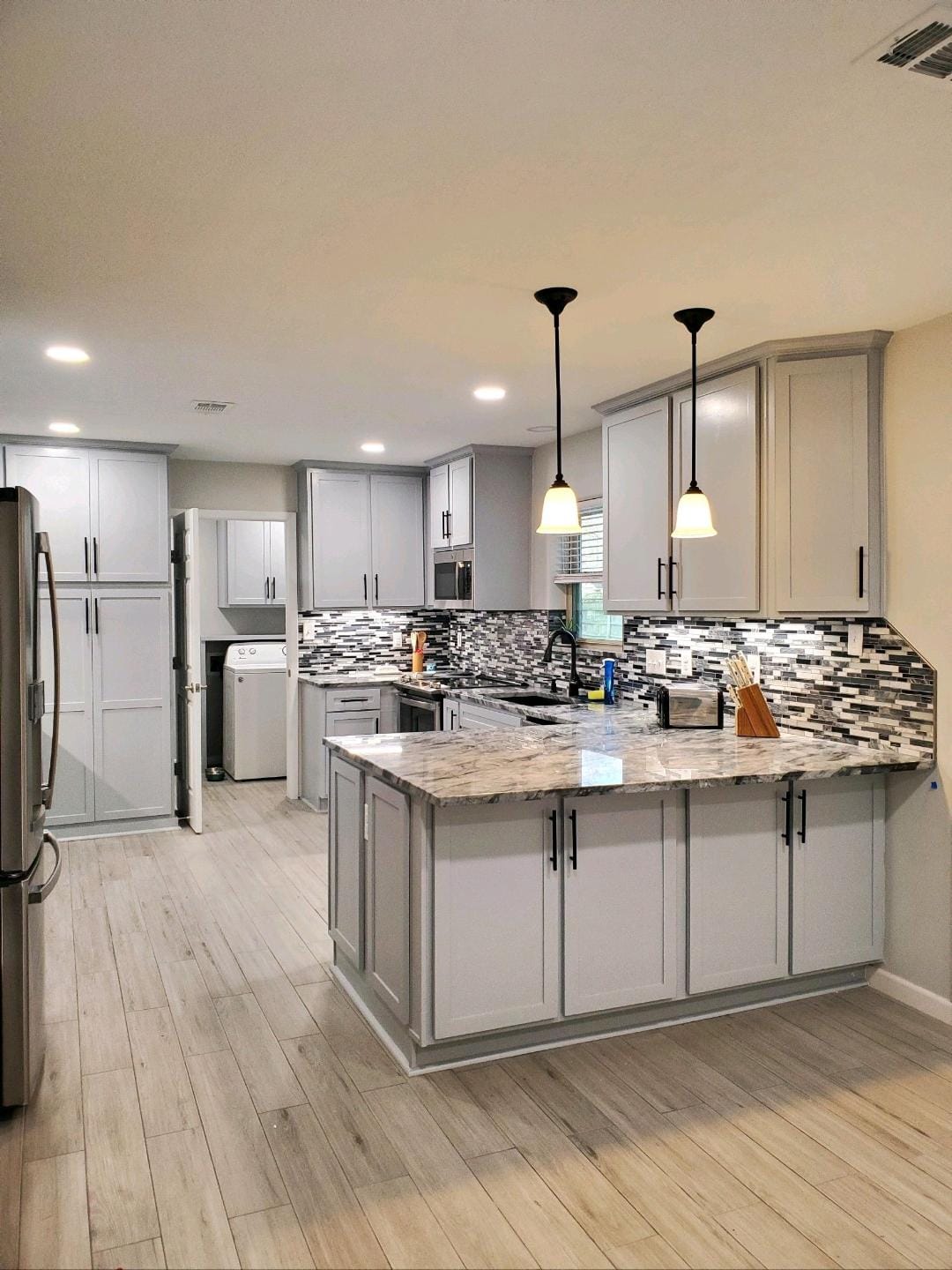 A kitchen with white cabinets , granite counter tops , and stainless steel appliances.