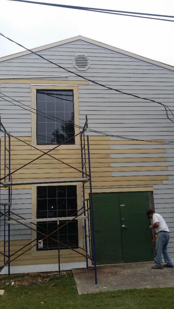 A man is painting the side of a house.
