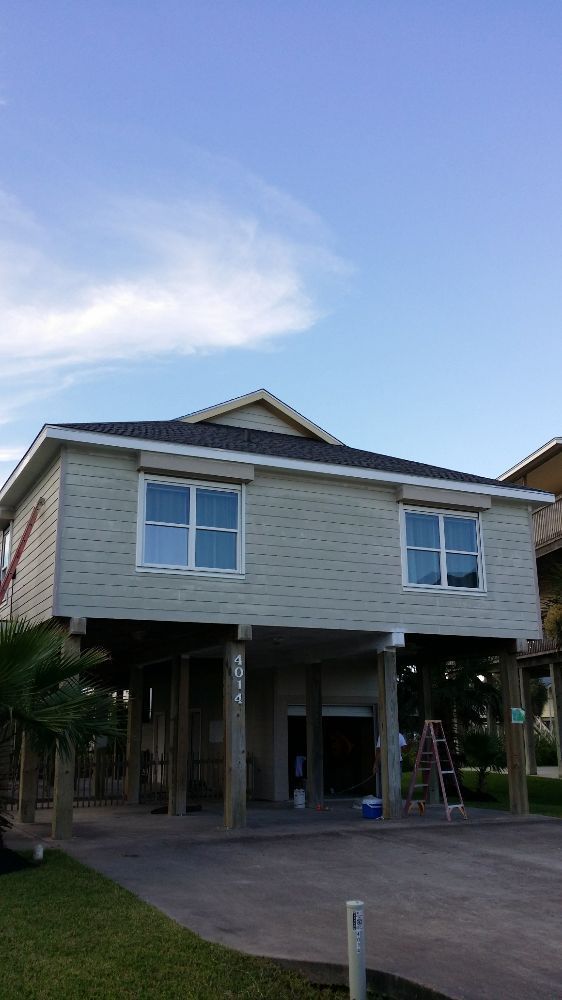 A house with a garage underneath it is being painted.