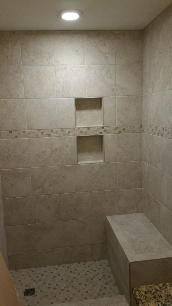 A bathroom with a walk in shower and a bench.