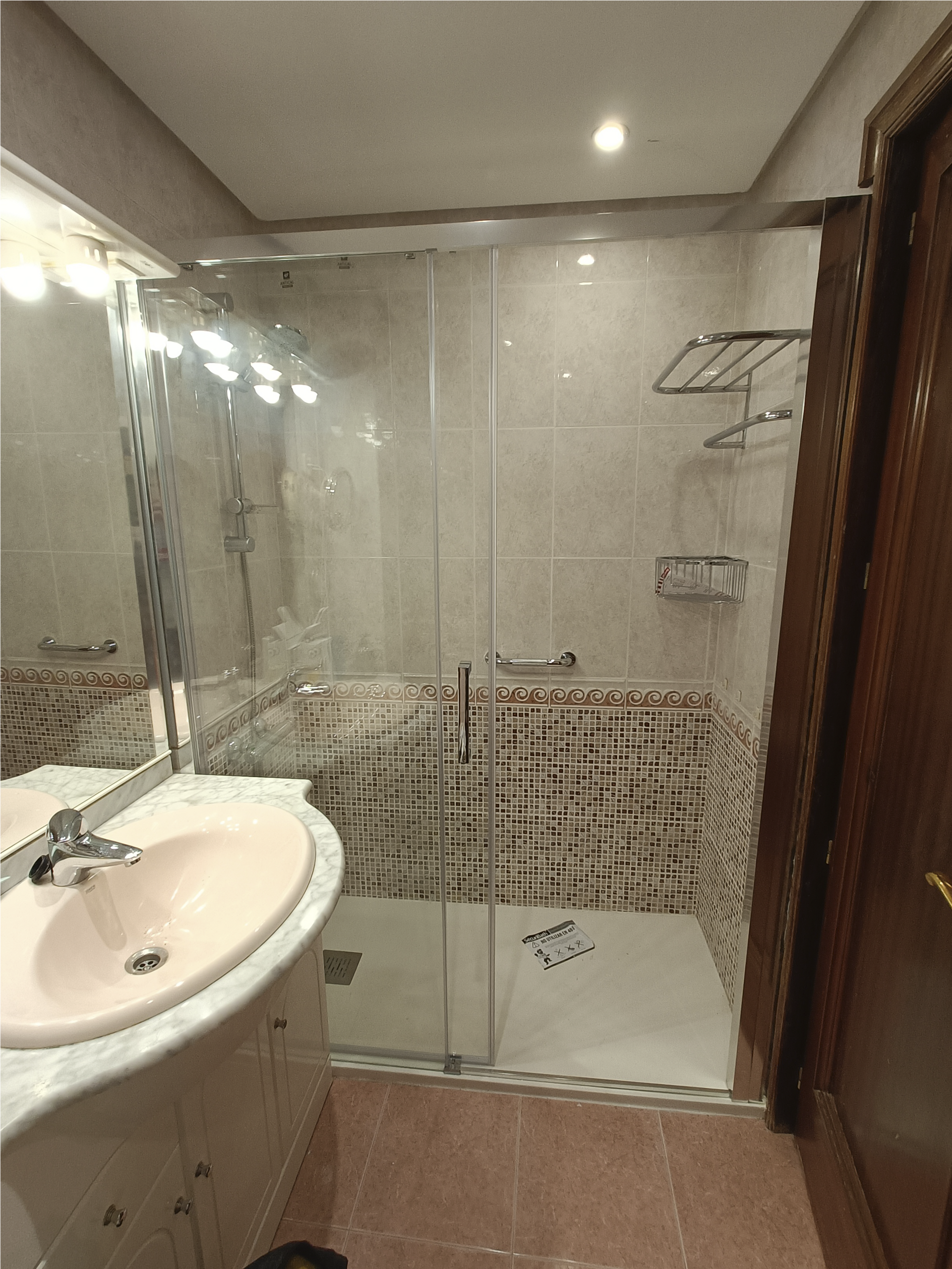 Un baño con lavabo, espejo y cabina de ducha.