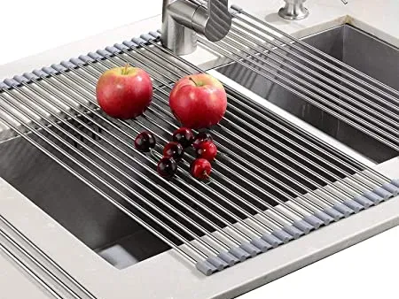 Dos manzanas y cerezas están colocadas sobre una rejilla de secado de acero inoxidable en un fregadero de la cocina.