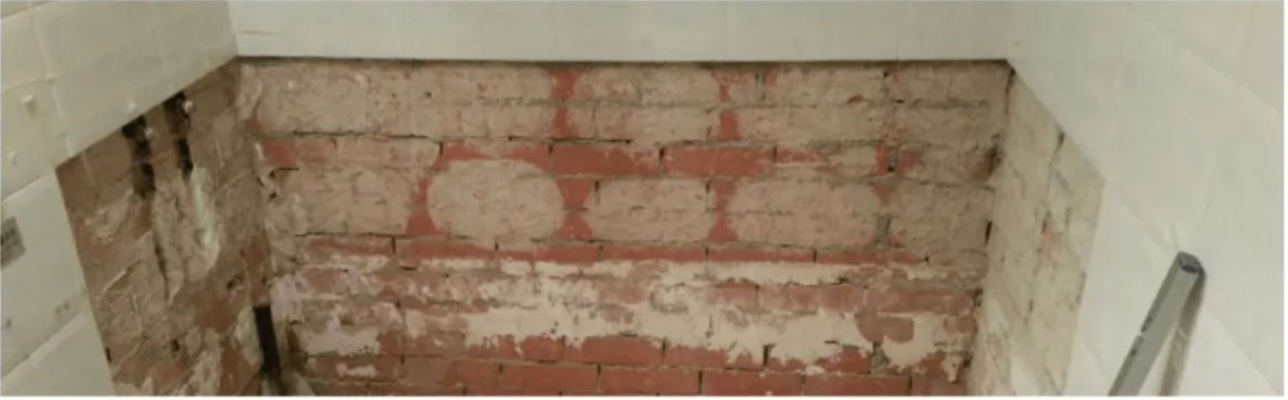 Una habitación con una pared de ladrillos y una pared blanca.