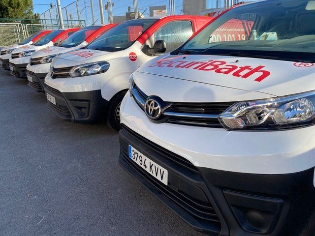 Una fila de furgonetas Toyota están estacionadas en un estacionamiento.