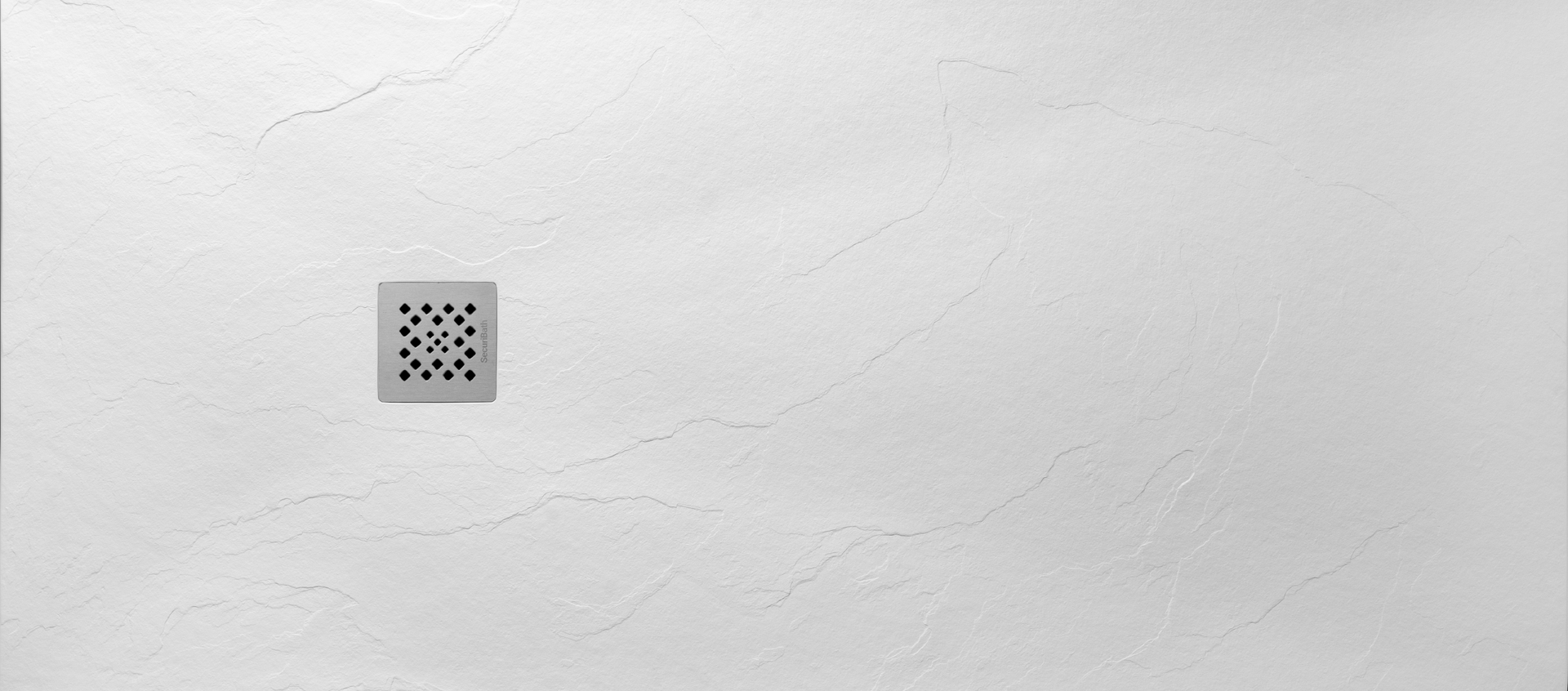 Un plato de ducha blanco con desagüe cuadrado sobre una pared blanca.