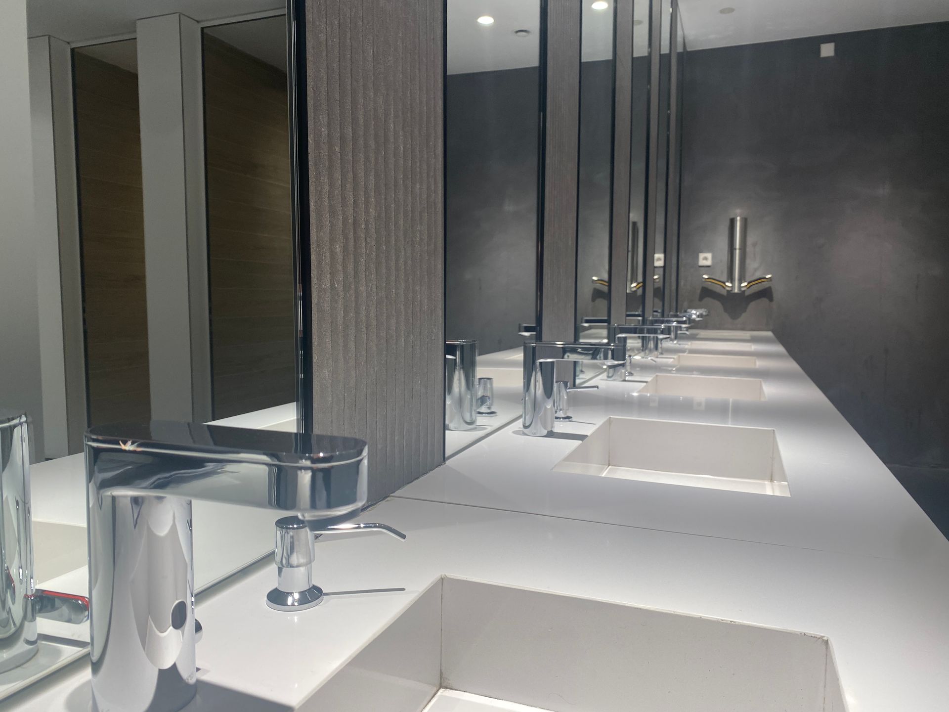 Un baño con una hilera de lavabos y espejos.