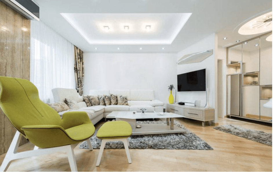 Un salón con sofá, sillón, mesa de centro y televisión.