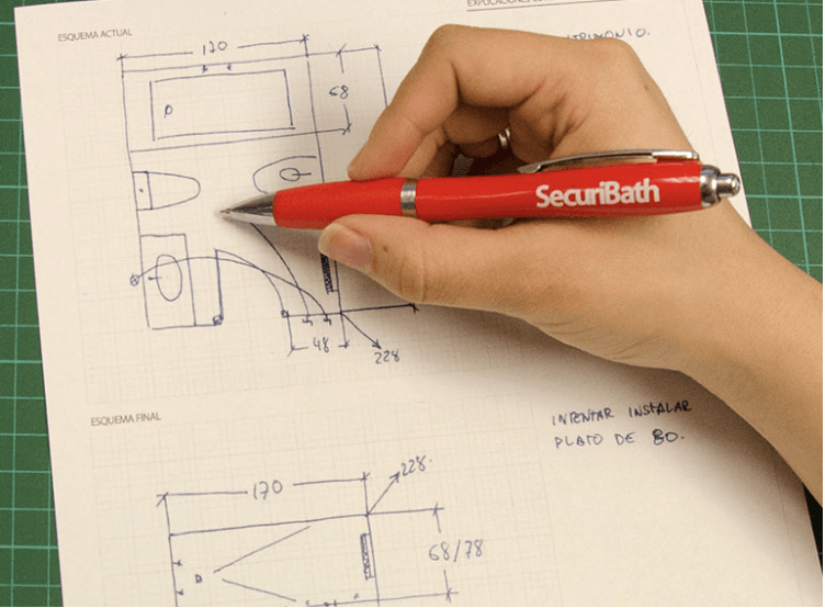 Una persona está escribiendo en una hoja de papel con un bolígrafo rojo que dice securbath