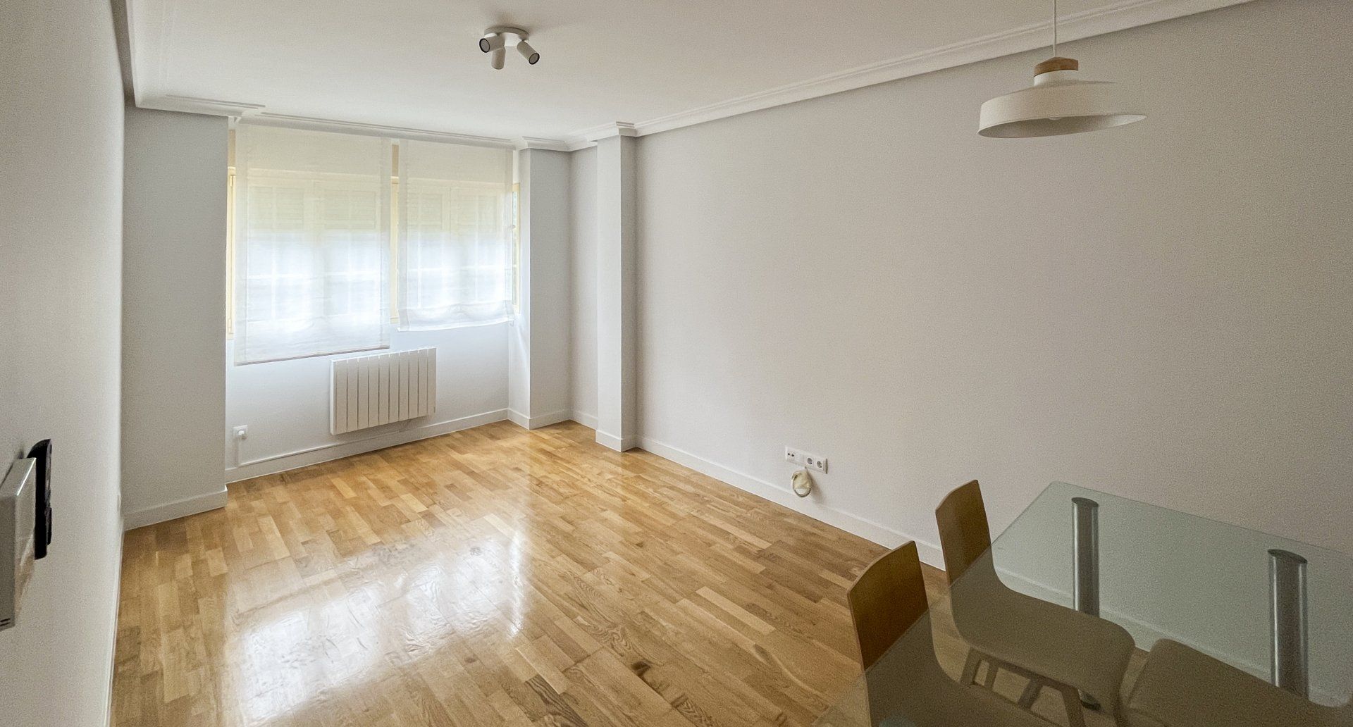 Un salón vacío con mesa de comedor y sillas.