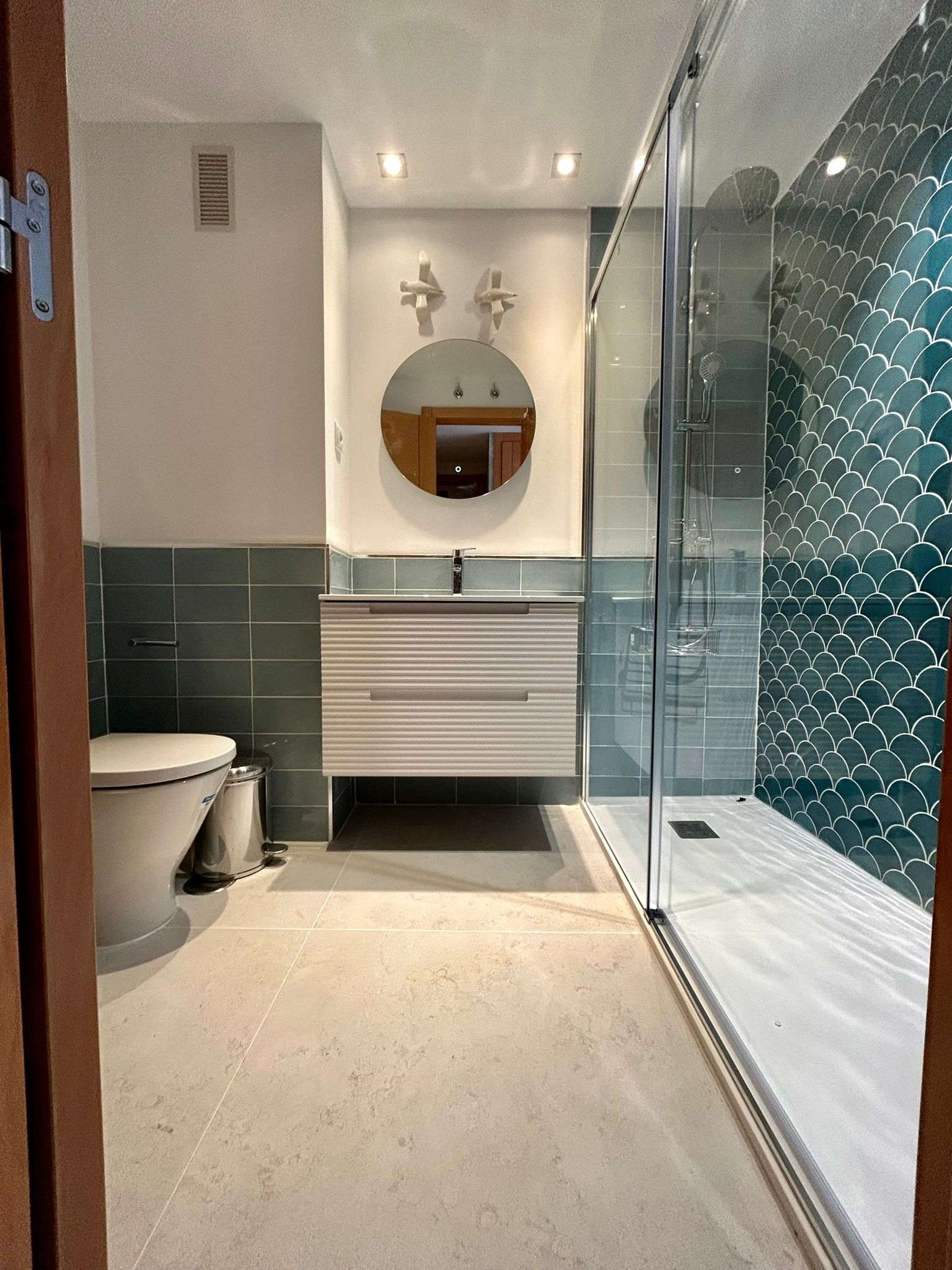 Un baño con inodoro, lavabo, espejo y ducha.