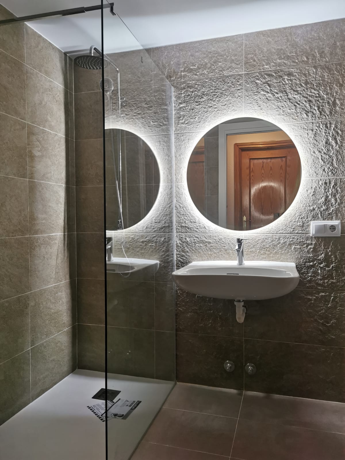 Un baño con lavabo, espejos y ducha.