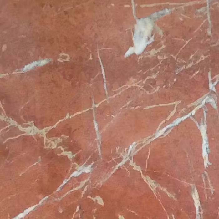Un primer plano de un suelo de mármol rojo con vetas blancas.