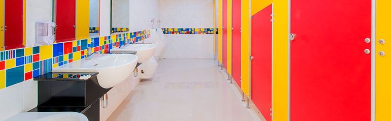 Un baño con puestos y lavabos rojos, amarillos y azules.