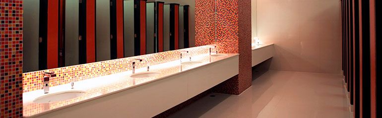 Un baño con una larga hilera de lavabos y espejos.