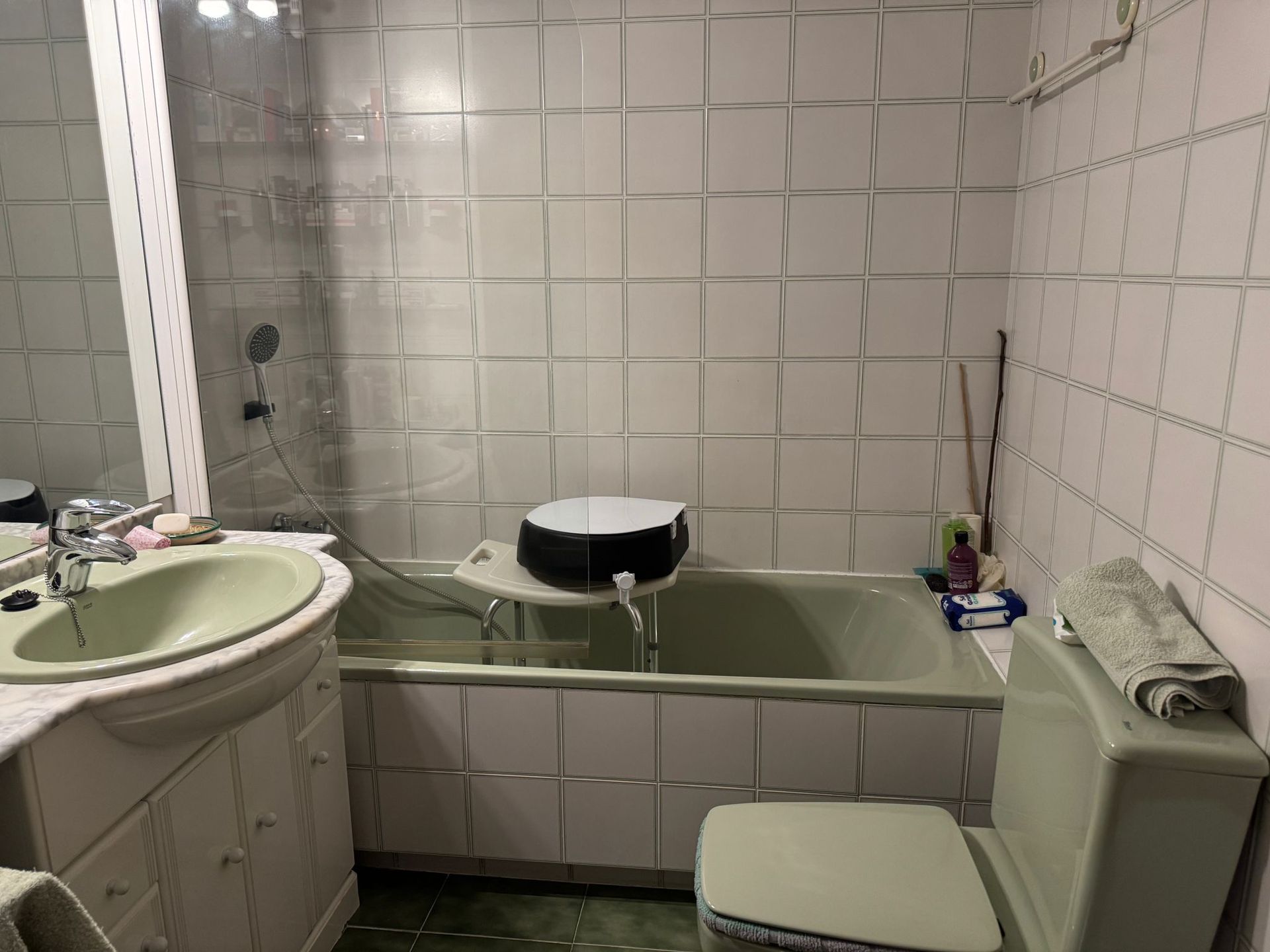 Baño con bañera, lavabo e inodoro verdes, paredes de azulejos blancos.