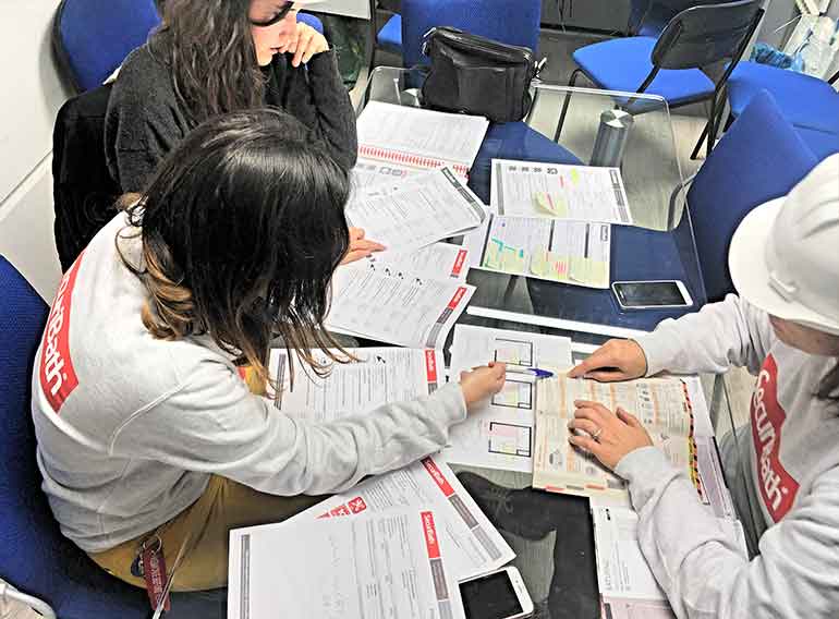 Un grupo de personas está sentada alrededor de una mesa con papeles encima.