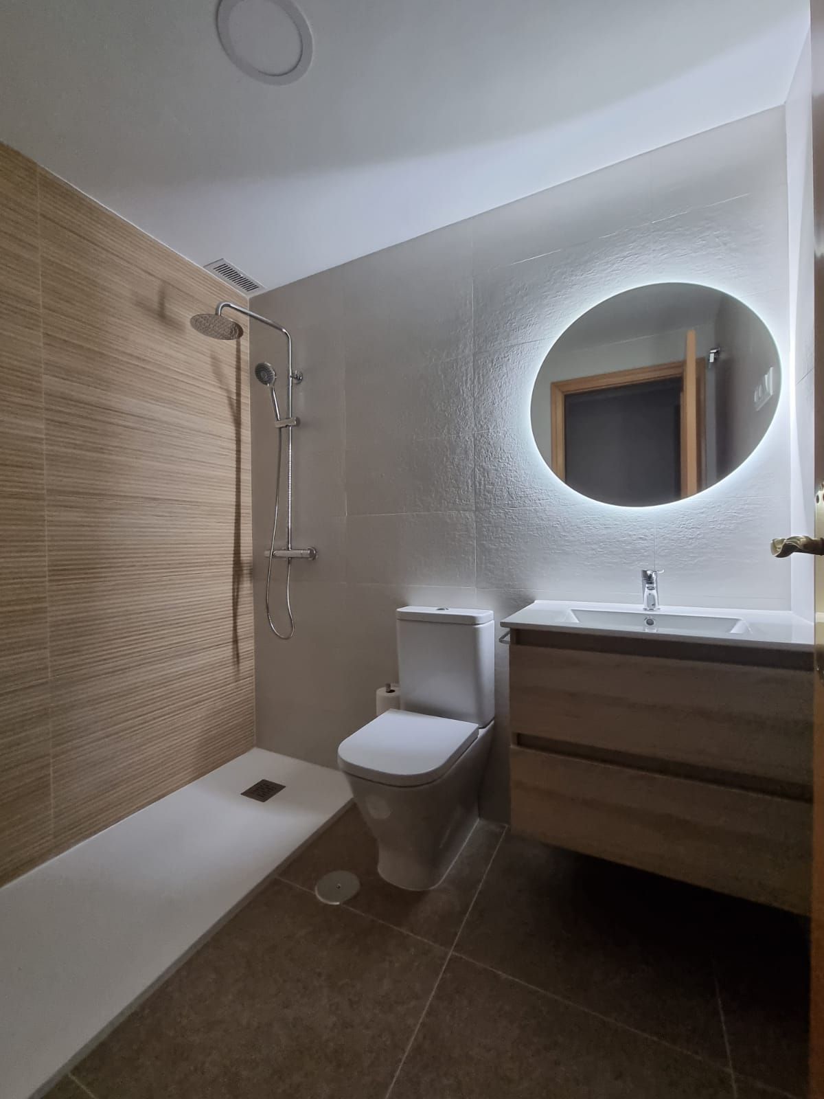 Un cuarto de baño con inodoro, lavabo, ducha y espejo.
