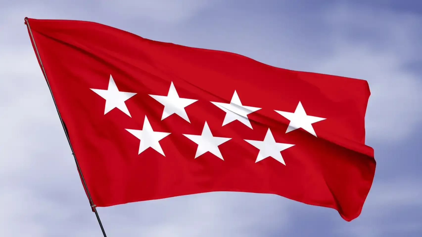 Una bandera roja con estrellas blancas ondea en el viento.