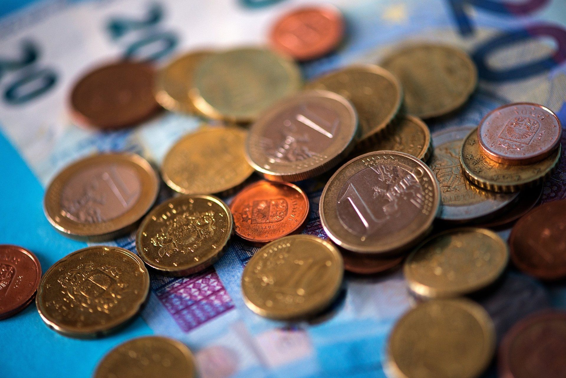 Sobre un billete de 20 euros hay un montón de monedas.