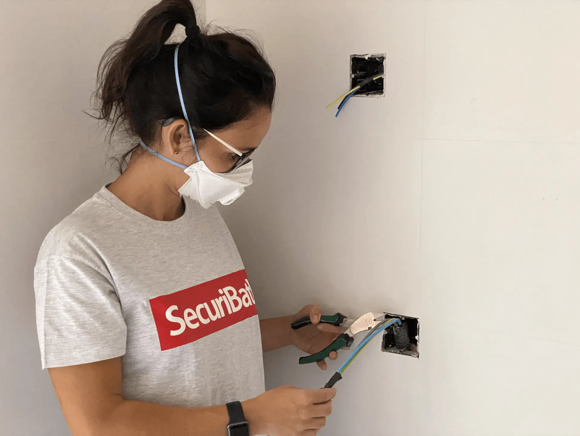 Una mujer con máscara y gafas está trabajando en una pared.