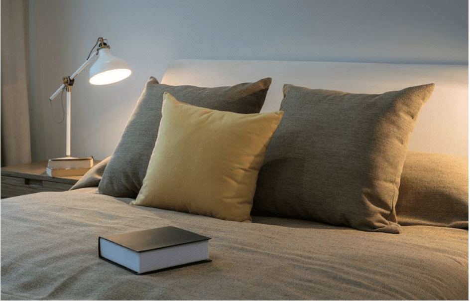 Una cama con almohadas y un libro encima.