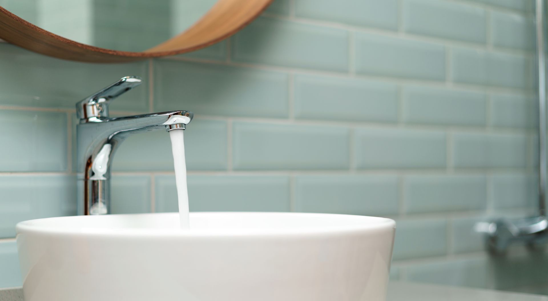 Un lavabo de baño con agua corriendo del grifo y un espejo.