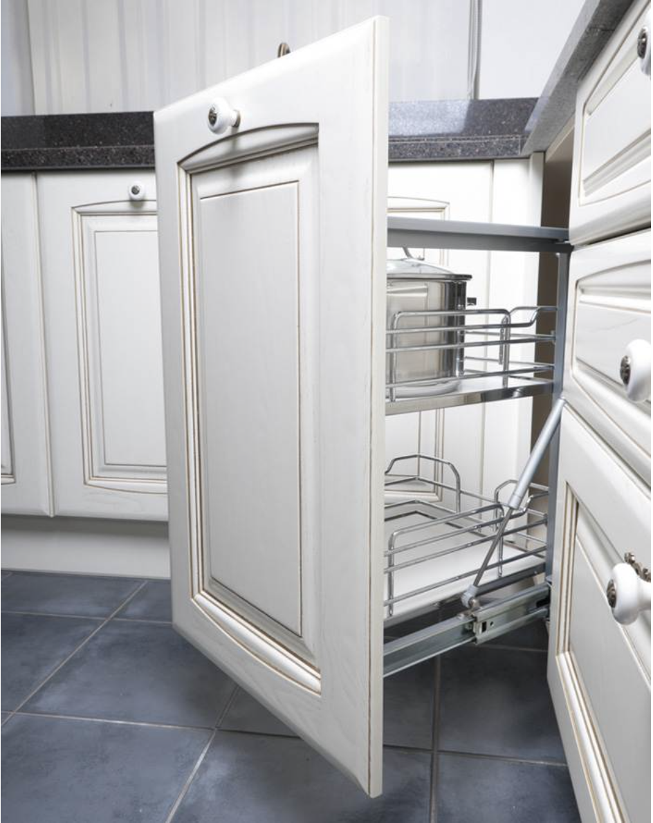 Una cocina con gabinetes blancos y una canasta extraíble.