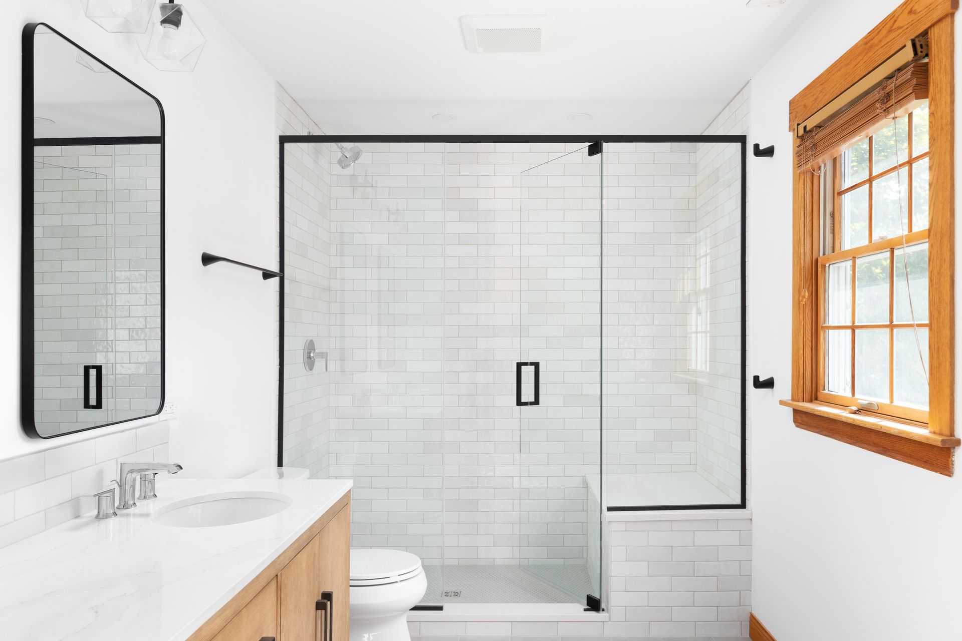 Un baño con plato de ducha, lavabo, espejo y ventana.
