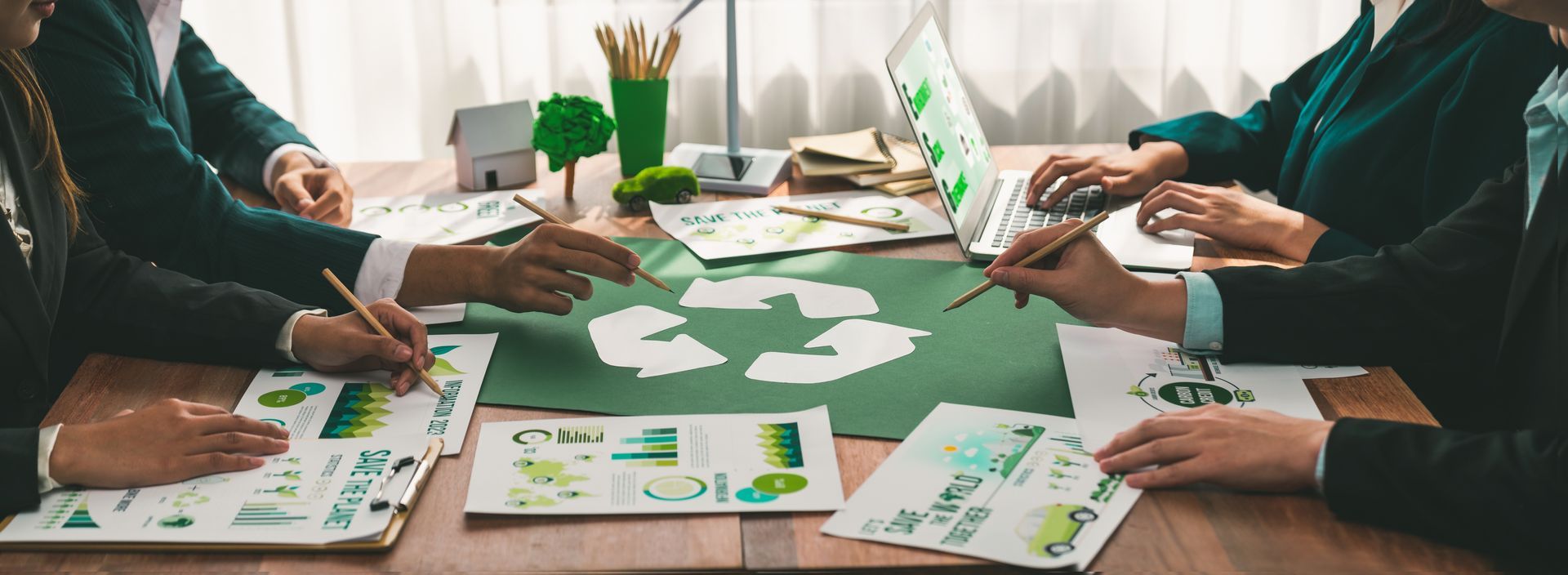 Un grupo de personas está sentada alrededor de una mesa con un símbolo de reciclaje.