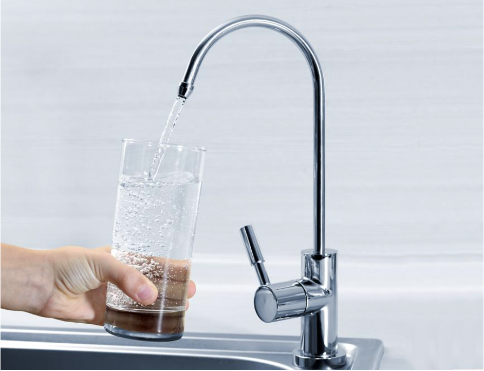 Una persona vierte agua en un vaso de un grifo.