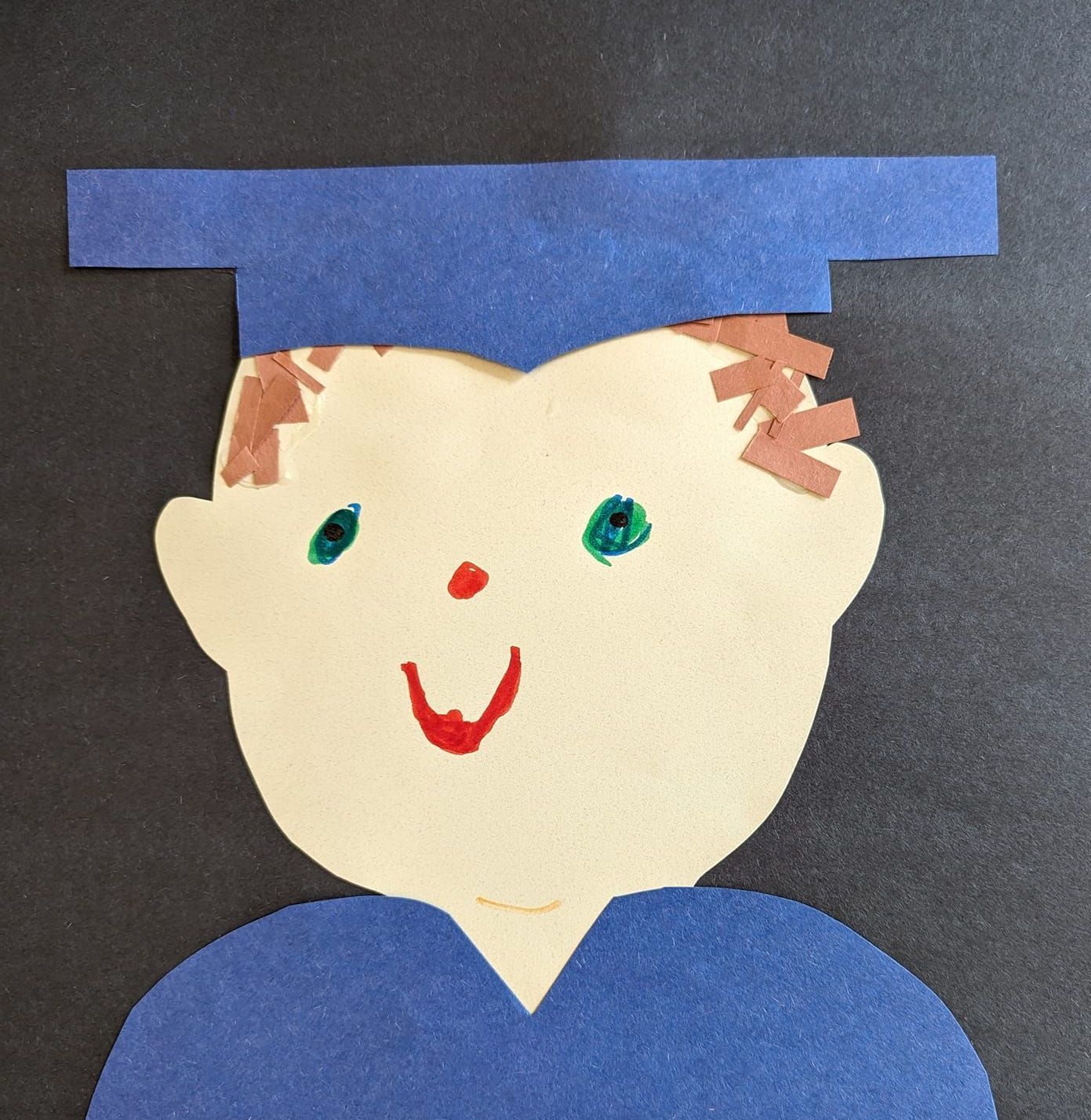 A child 's drawing of a boy wearing a graduation cap and gown