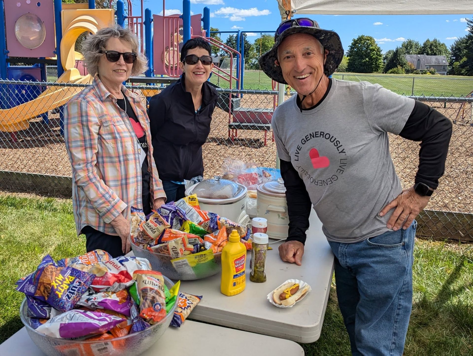 A group of people are standing around a table filled with food.