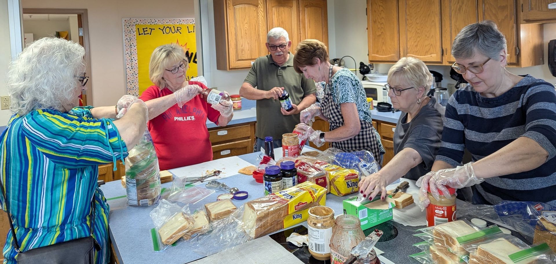 A group of people are making sandwiches in a kitchen.