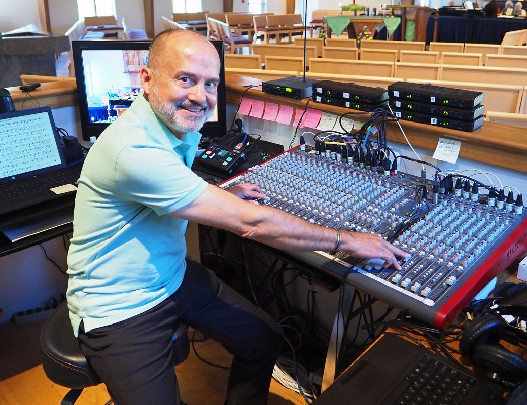A man in a green shirt is sitting in front of a mixer.