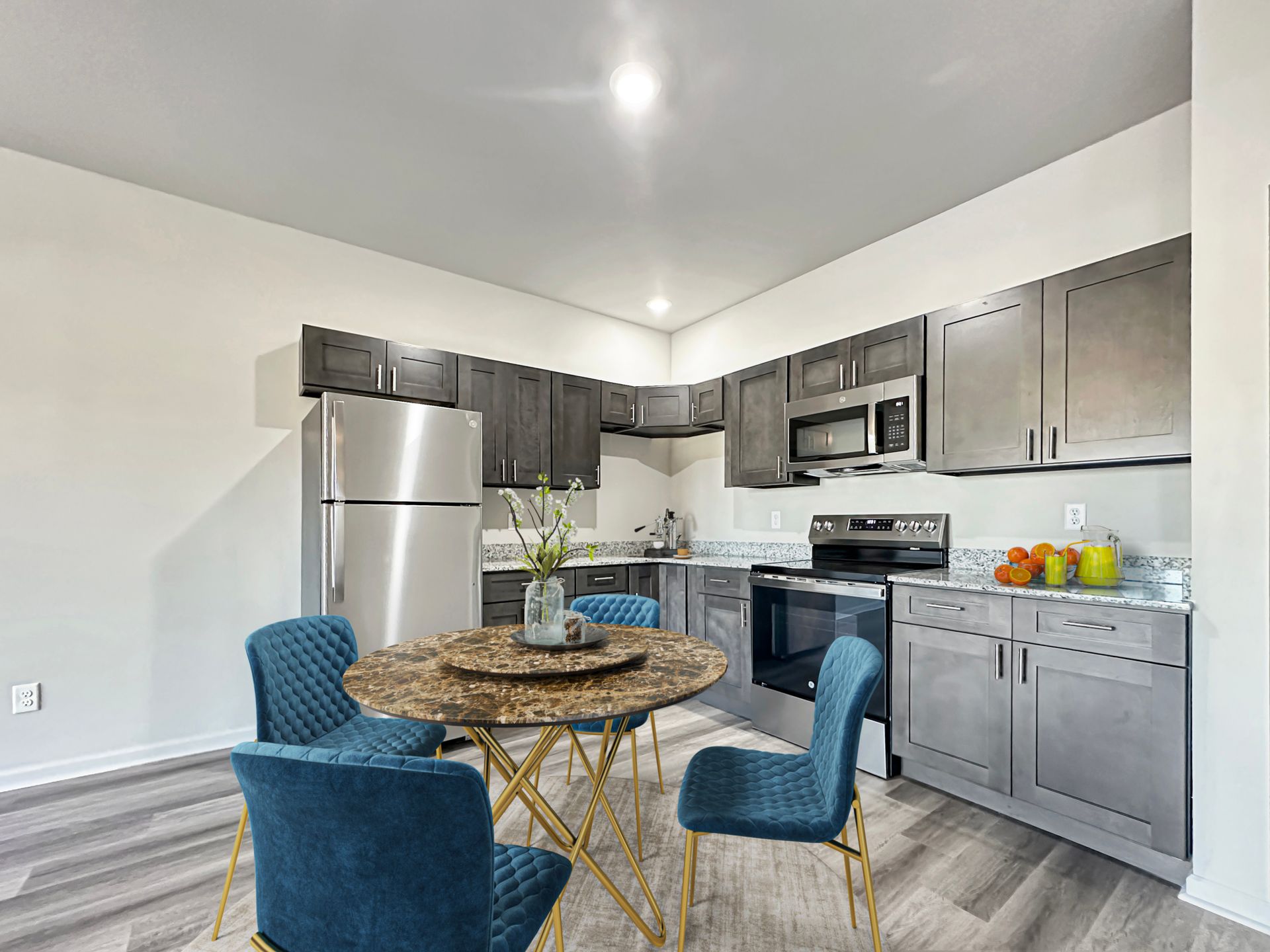 Modern kitchen with stainless steel appliances, gray cabinets, and a round table with blue chairs