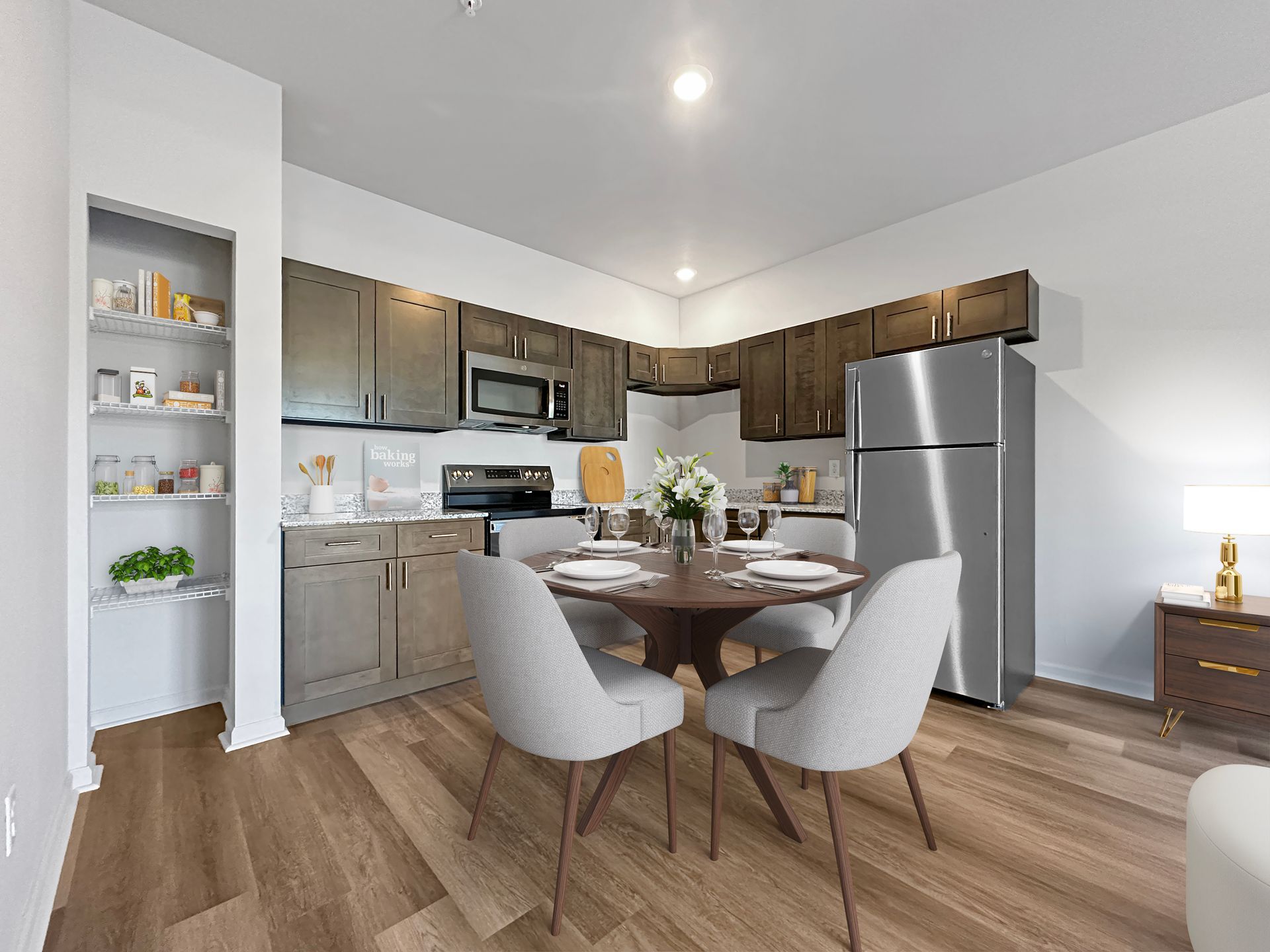 Modern kitchen and dining area with gray cabinets, stainless appliances, round table, and two chairs