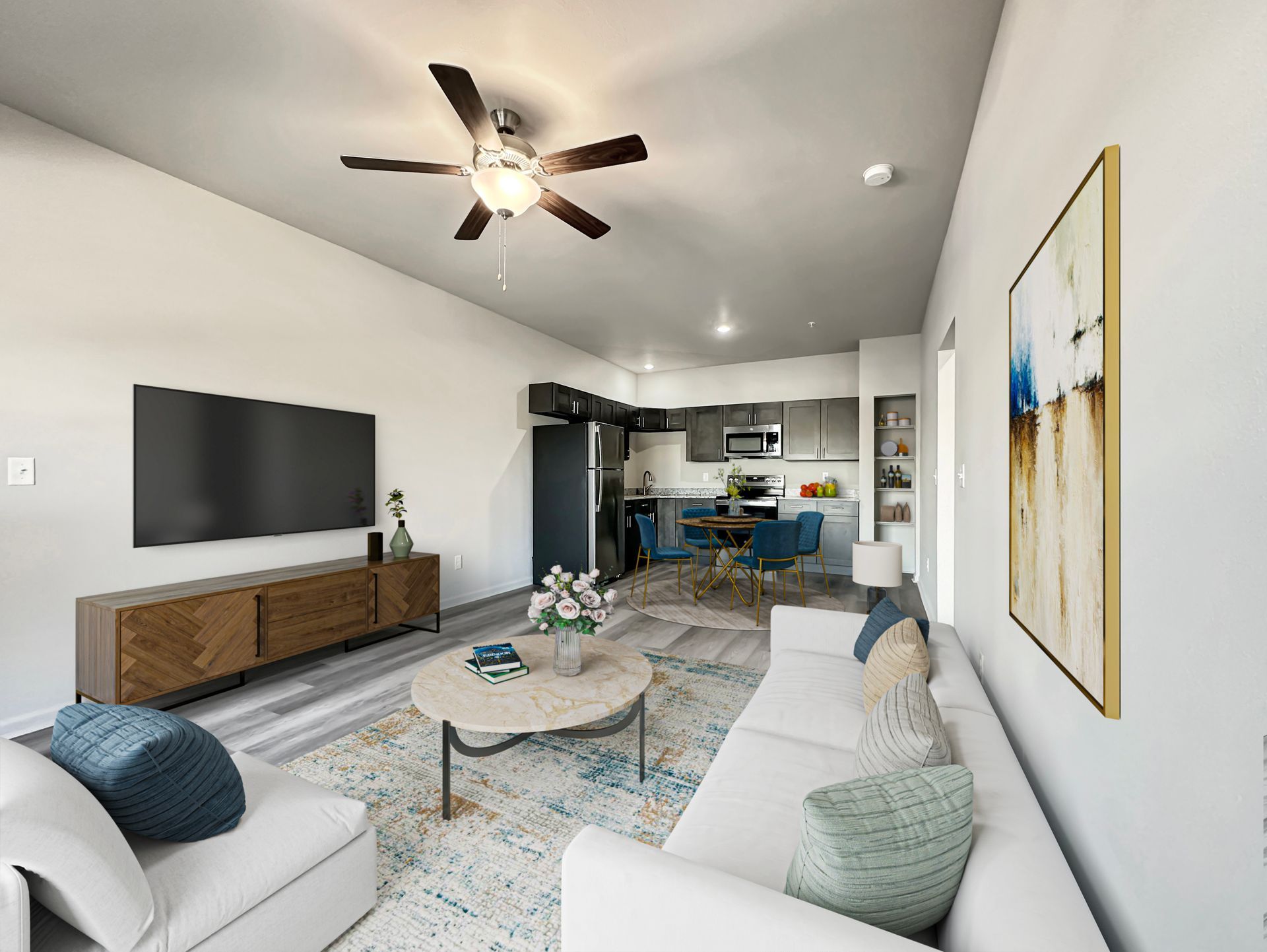 Bright modern living room with white sofas, TV, coffee table, ceiling fan, and open kitchen area