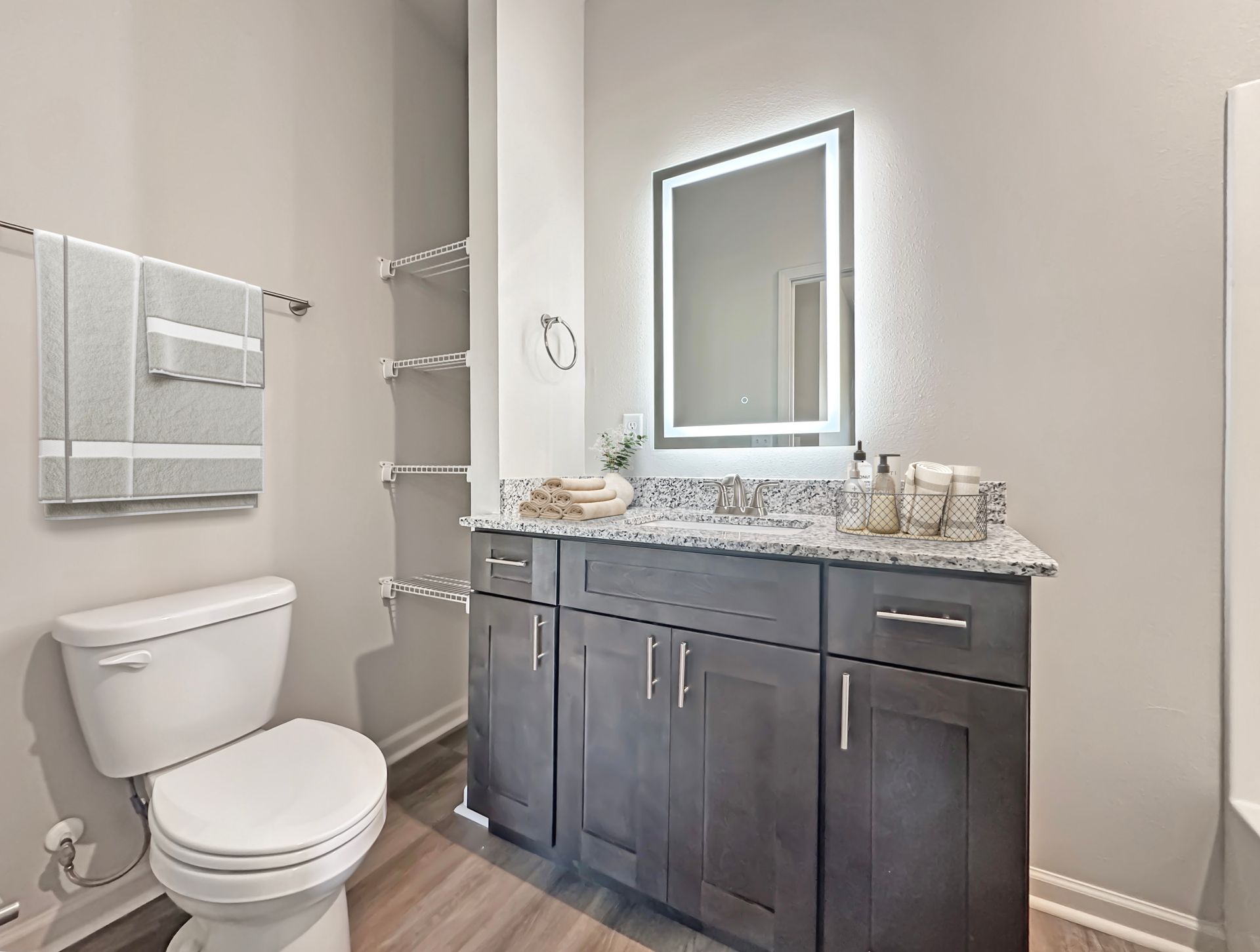 Modern bathroom with white toilet, dark vanity, mirror, and light gray walls