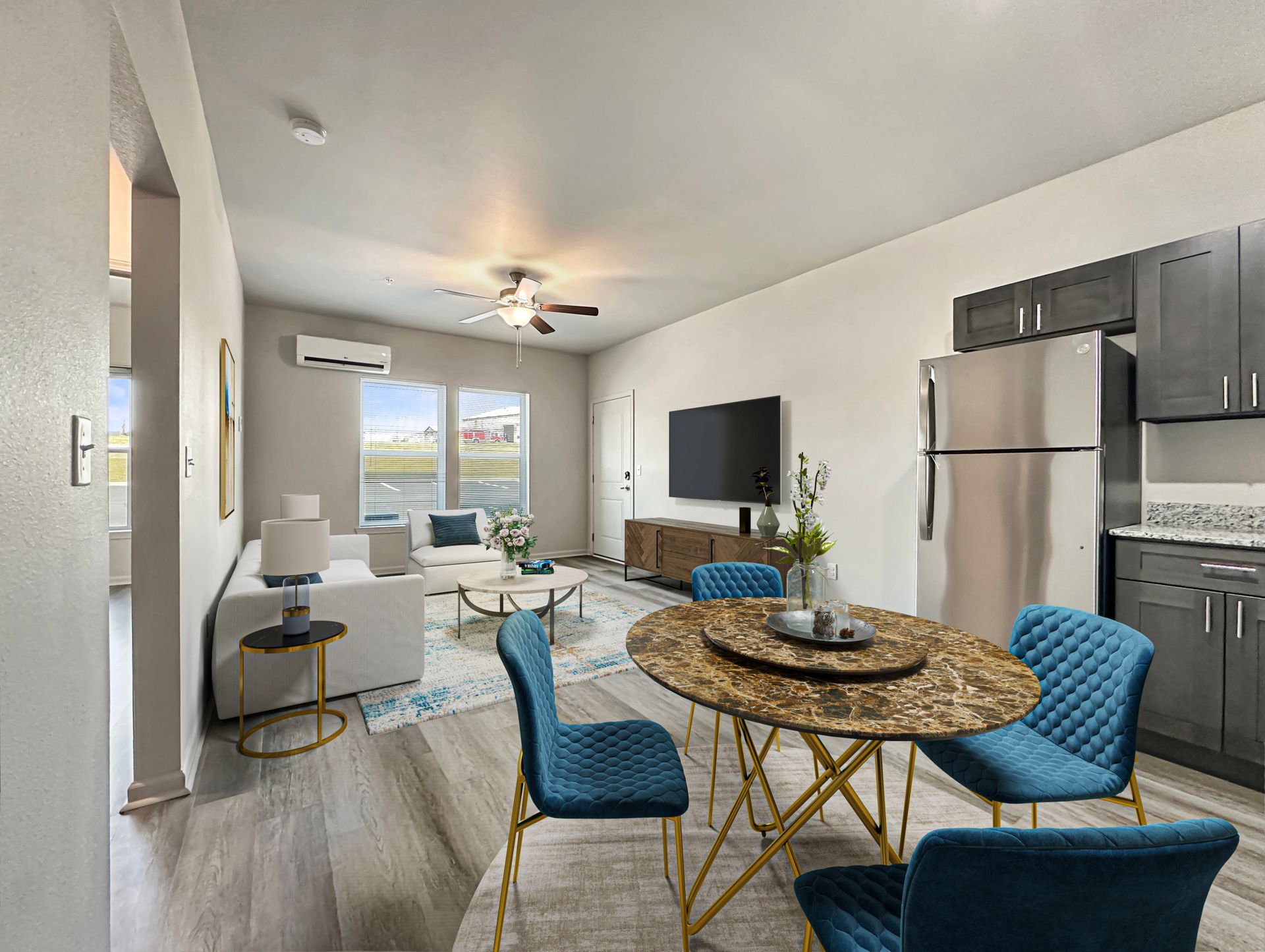 Modern apartment living room and kitchen with blue chairs, round dining table, sofa, TV, and balcony view