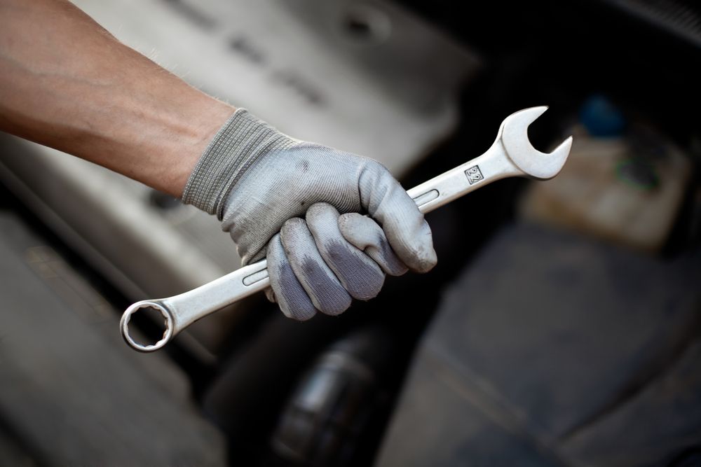 A Person Wearing Gloves Is Holding A Wrench In Their Hand — Jasco Automotive In Bowen, QLD