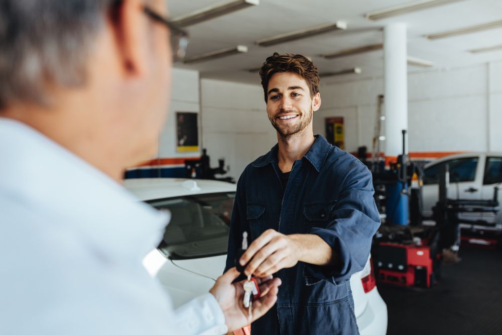 A Man Is Giving A Car Key To A Mechanic In A Garage — Jasco Automotive In Bowen, QLD