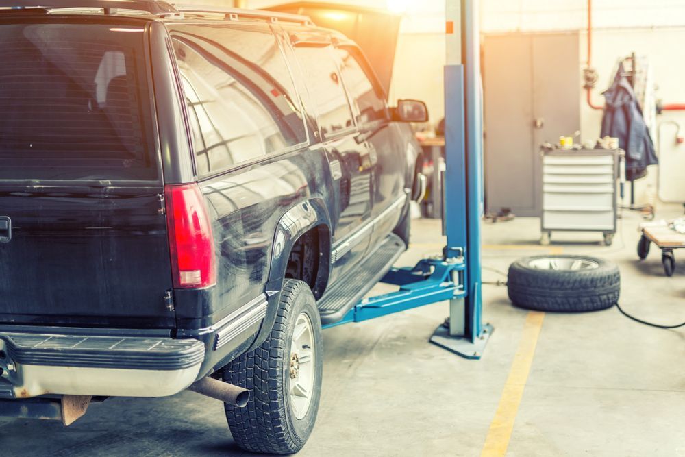 A Black SUV Is Sitting On A Lift In A Garage — Jasco Automotive In Bowen, QLD