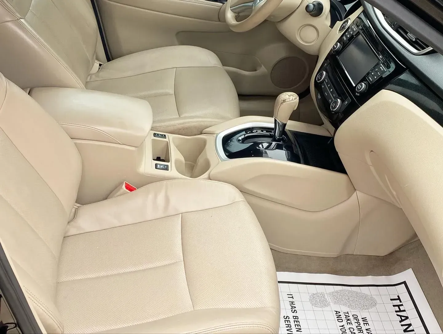 Beige car interior with front seats, center console, and dashboard view from the passenger side