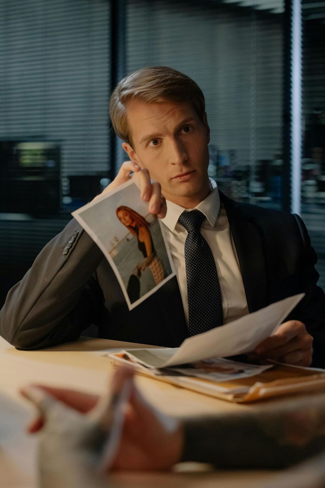 A man in a suit and tie is sitting at a table holding a picture of a woman.