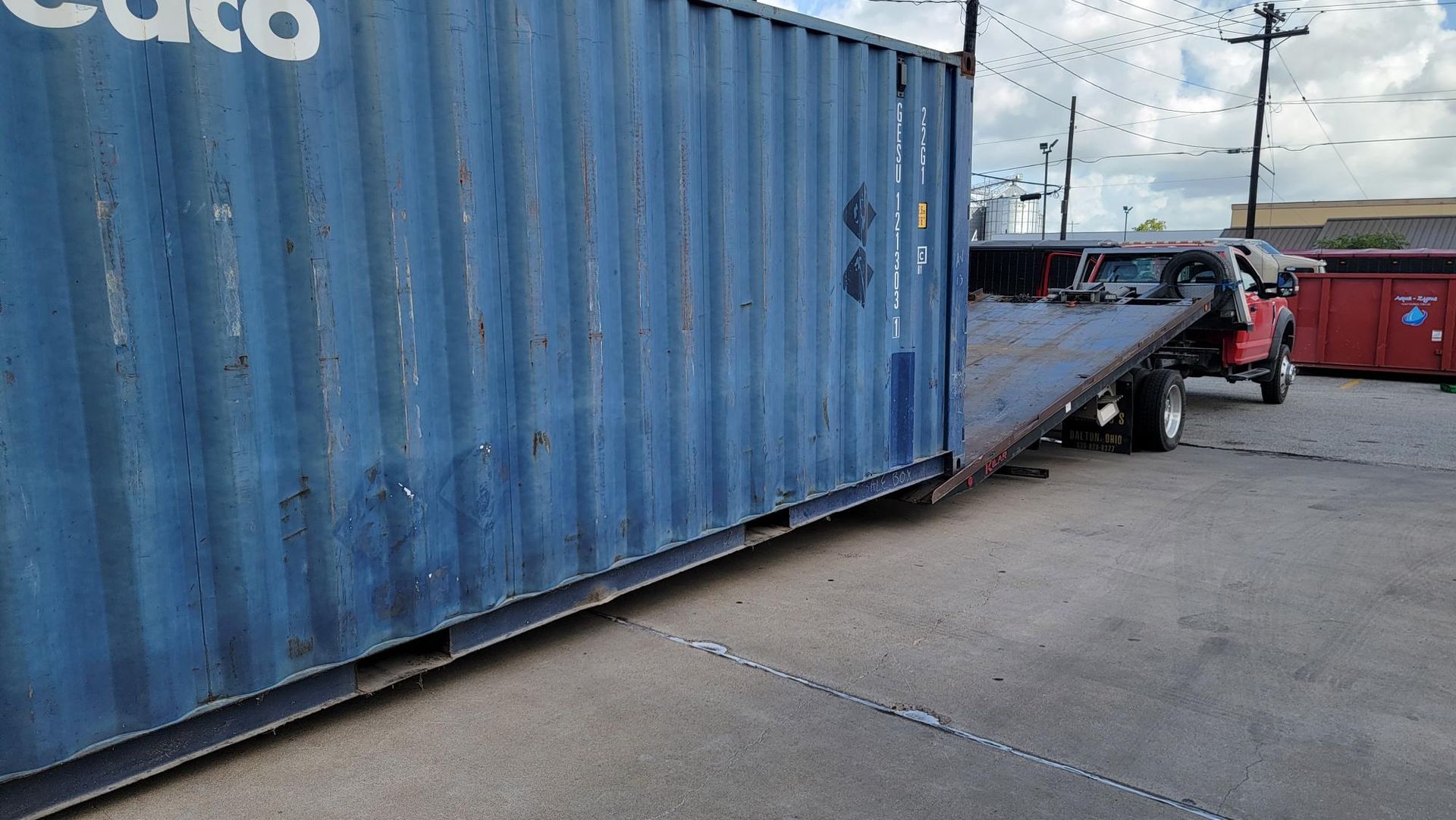 Blue shipping container being loaded onto a truck in an industrial yard