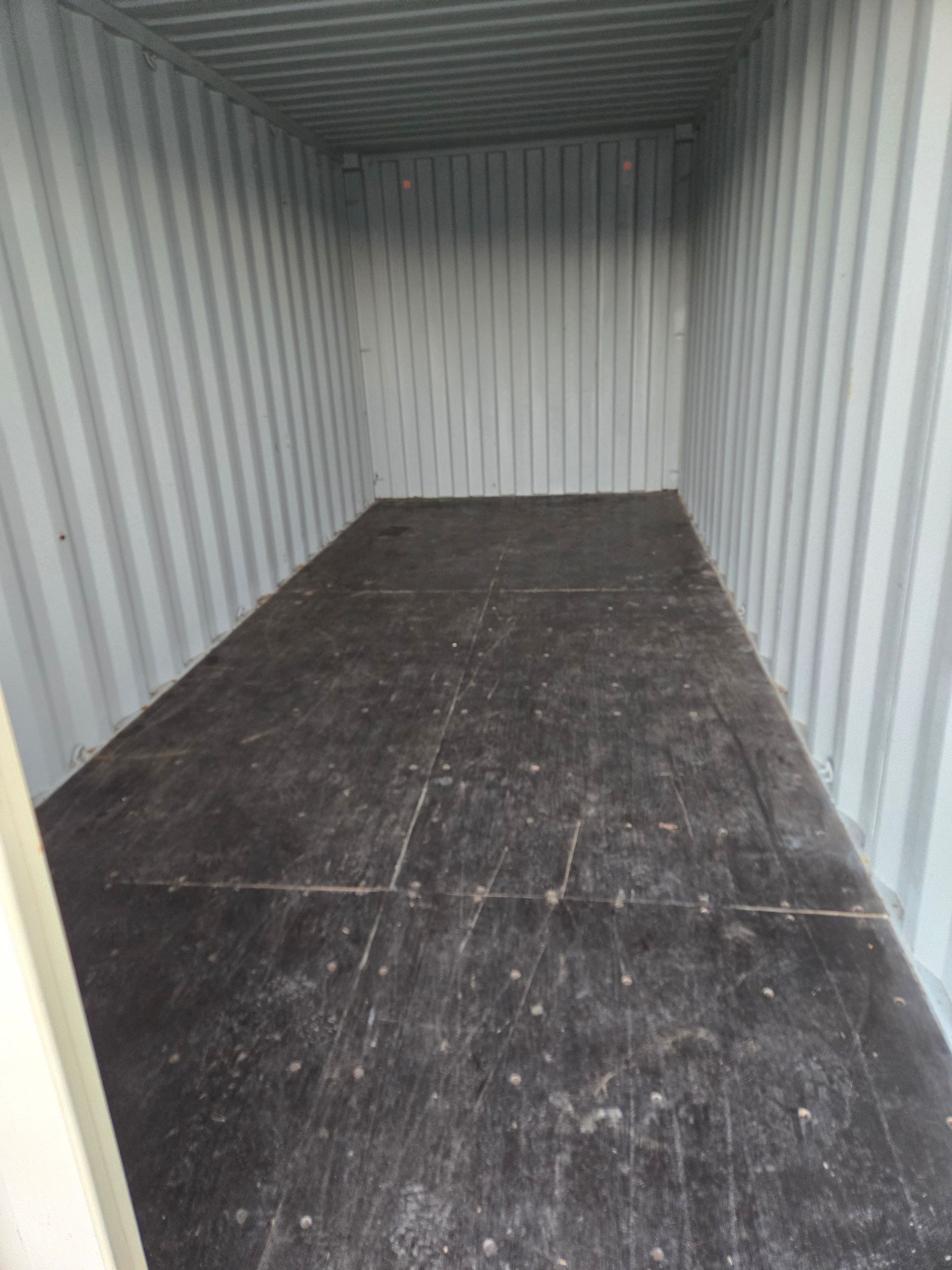 Empty corrugated metal container with a dark floor and open doorway