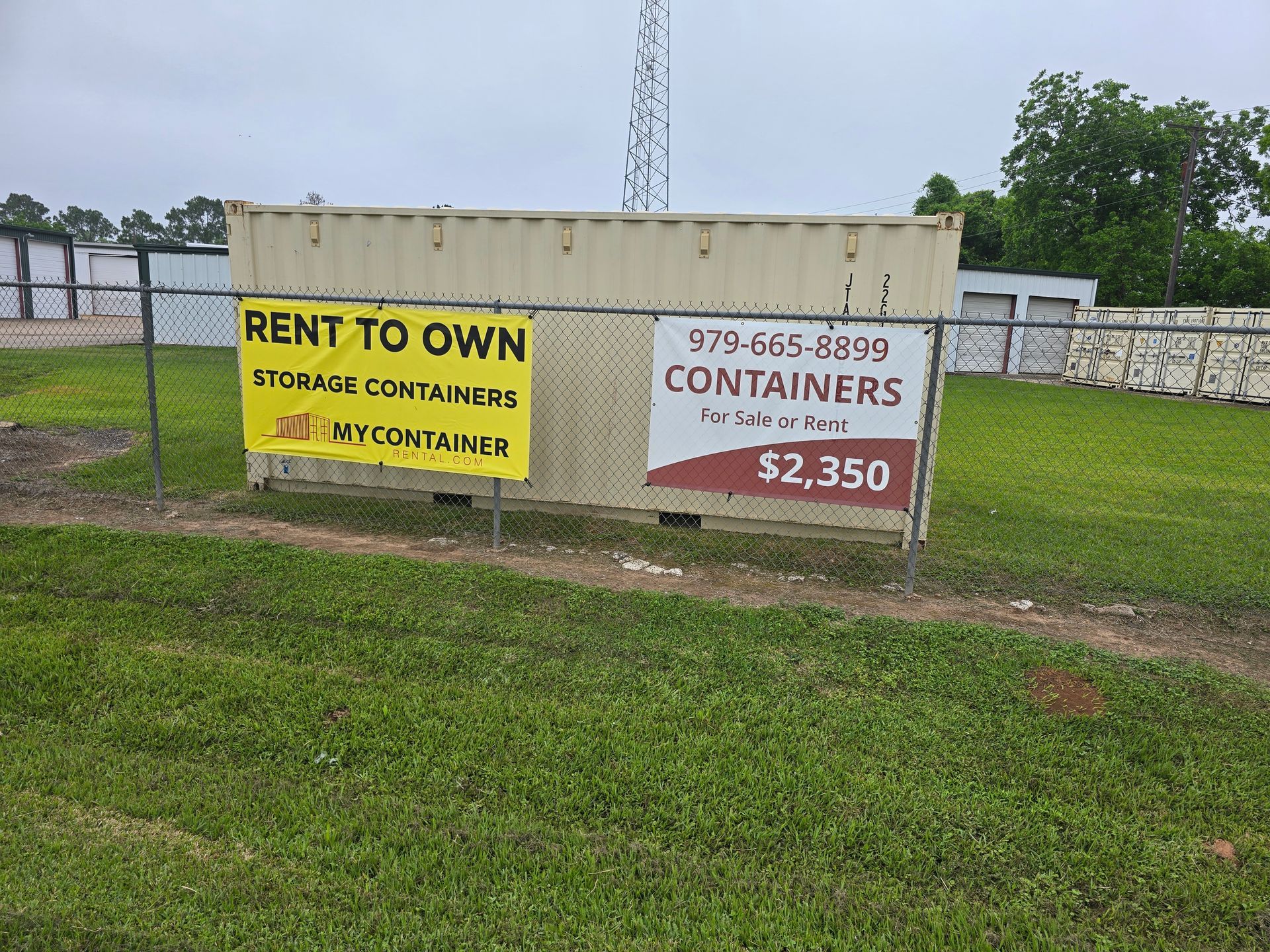Rented shipping container on grass with yellow and white “Rent to Own” signs and phone number.